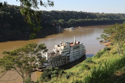 abandoned ship docked on a wide, brown river